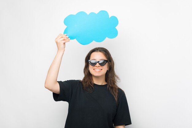 Junge Frau mit Sonnenbrille hält eine Papierwolke über ihrem Kopf.