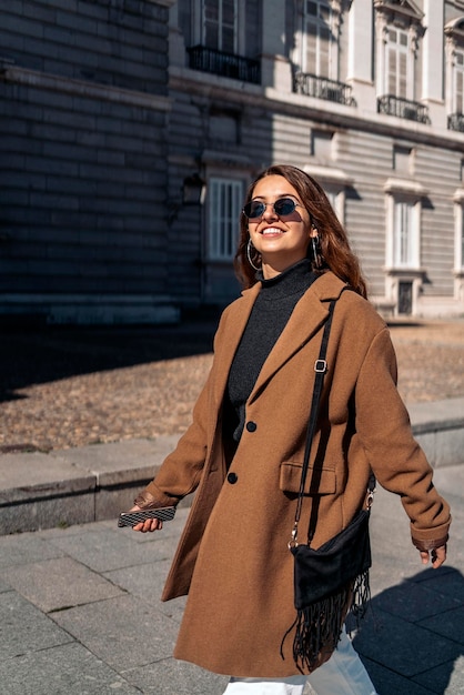 Junge Frau mit Sonnenbrille steht auf einer Straße in der Stadt