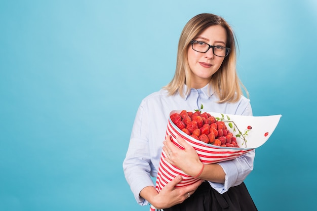 Junge Frau mit Strauß Erdbeeren auf blauem Hintergrund