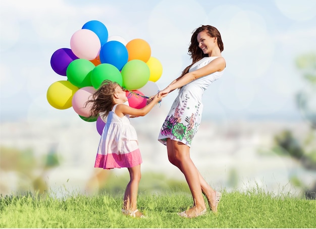 Junge Frau mit süßem kleinen Mädchen und bunten Luftballons