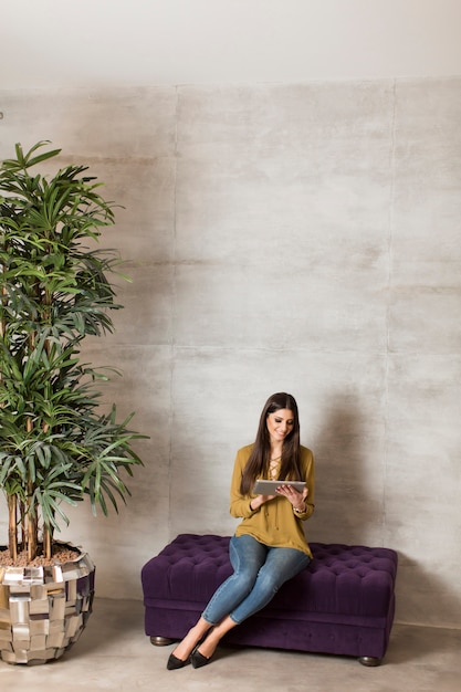 Junge Frau mit Tablette auf dem Sofa