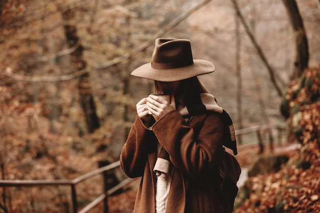 Junge Frau mit Tasse Kaffee in einem Herbstsaisonpark
