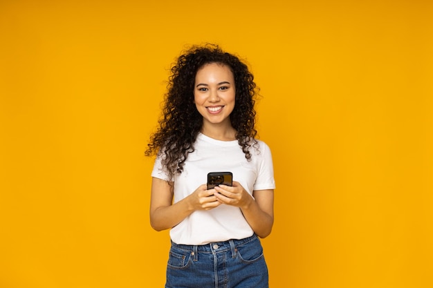 Junge Frau mit Telefon auf gelbem Hintergrund