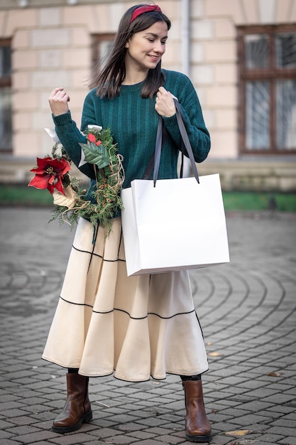 Junge Frau mit Weihnachtsgeschenken außerhalb der Weihnachtseinkäufe