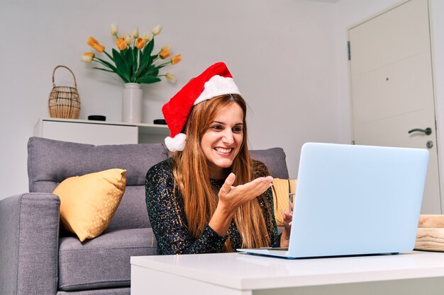 Junge Frau mit Weihnachtsmannhut macht einen Videoanruf an ihre Familie, um Weihnachten zu feiern.