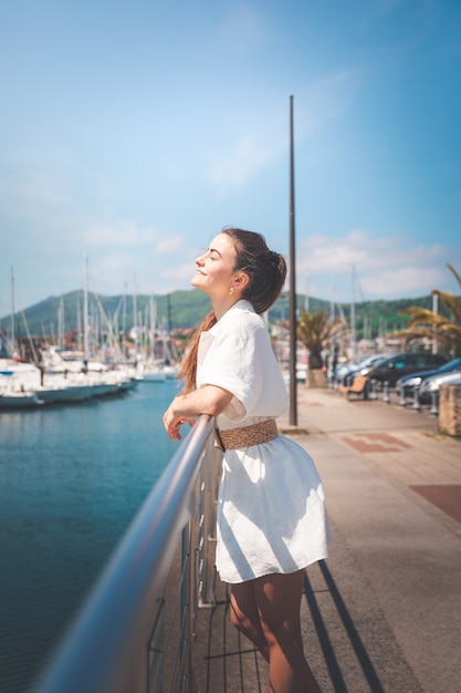 Junge Frau mit weißem Kleid in einem Hafen