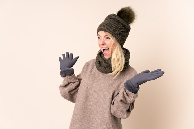 Junge Frau mit Wintermütze über lokalisiert mit Überraschungsgesichtsausdruck