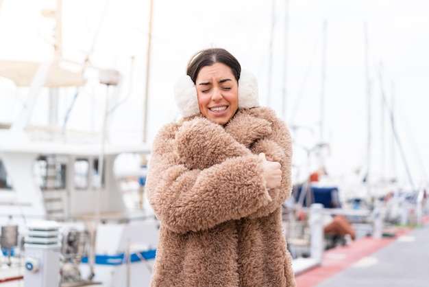 Junge Frau mit Wintermuffs beim Einfrieren im Freien