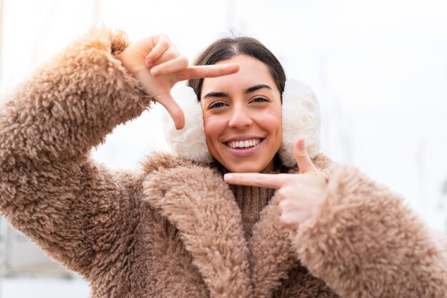 Junge Frau mit Wintermuffs im Freien mit Fokussierung auf das Framing-Symbol