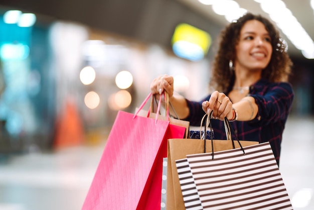Junge Frau nach dem Einkaufen mit Einkaufstüten geht in das Einkaufszentrum Spring shoopping