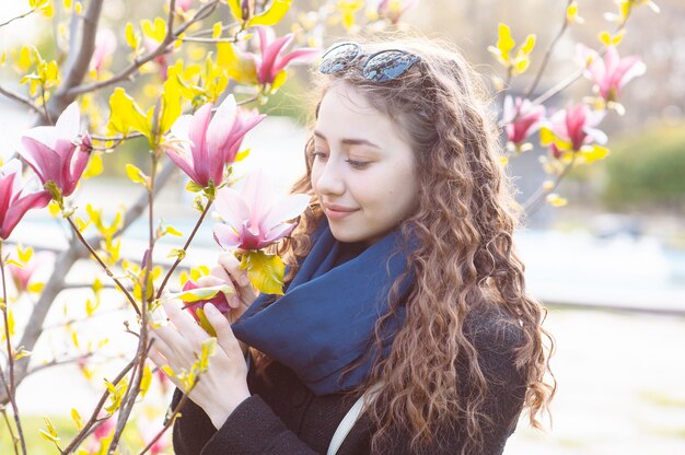 Junge Frau nahe blühendem Magnolienblumenbaum im Park