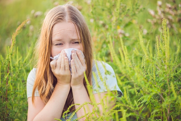 Junge Frau niest wegen einer Allergie gegen Ambrosia