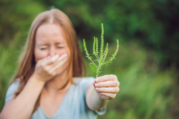 Junge Frau niest wegen einer Allergie gegen Ambrosia