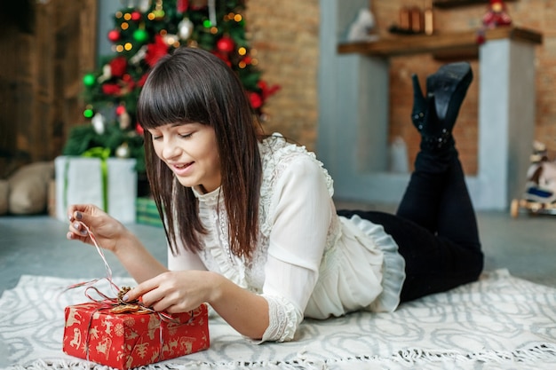 Junge Frau packt Geschenkbox aus. Konzept Neujahr, Frohe Weihnachten