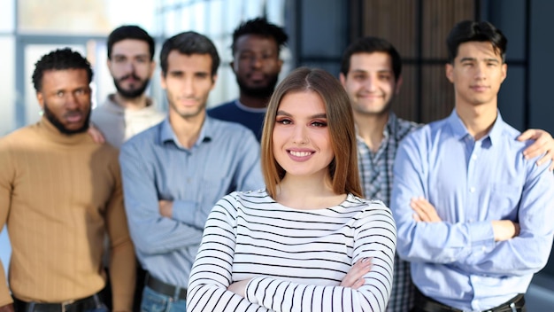 Junge Frau posiert für die Kamera vor ihrem Team im Büro