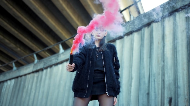Junge Frau posiert mit bunter Rauchbombe in der Kamera Mädchen protestiert im Freien