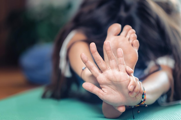 Junge Frau praktiziert drinnen Yoga. Sitzende Vorwärtsbeuge-Yoga-Pose Paschimottanasana