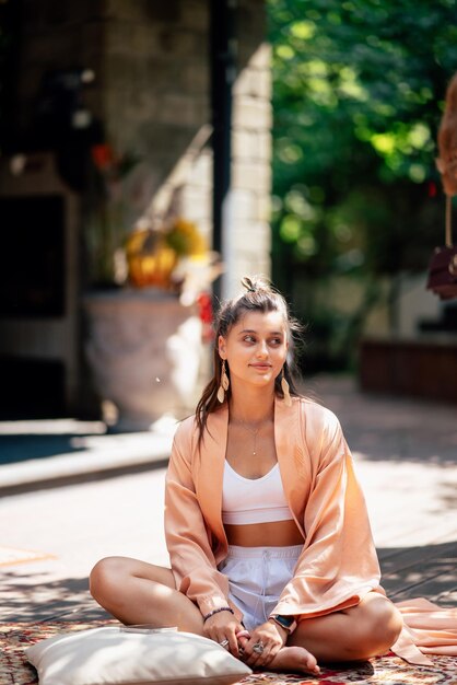 Junge Frau praktiziert Yoga auf einem hölzernen Podium sitzend