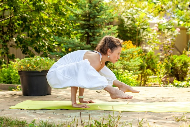 Junge Frau praktiziert Yoga im Innenhof eines Landhauses Titibhasana