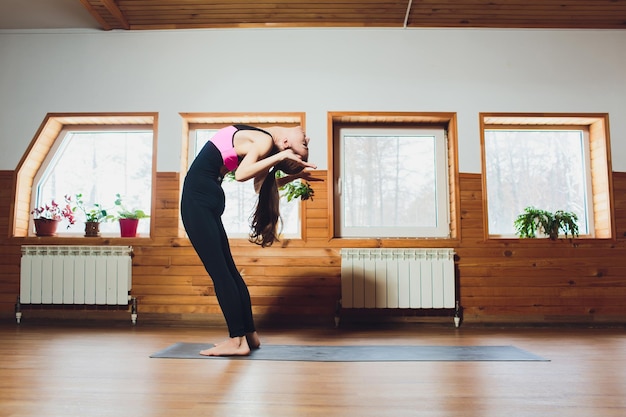 Foto junge frau praktiziert yoga, macht kopf-zu-knie-uttanasana-übung, steht vorwärts, bückt sich in die pose.