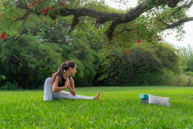 Junge Frau praktiziert Yoga und macht seitliche Ausfallschritte unter einem Baum in einem ParkWellness-Konzept