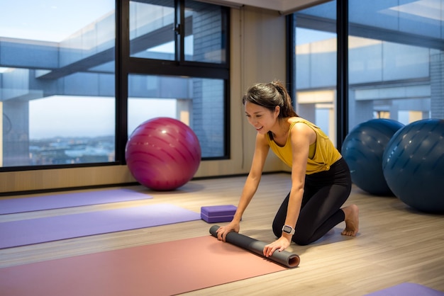 Junge Frau rollt eine Yoga-Matte nach einer Sportübung