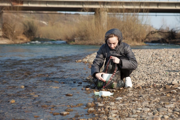 Junge Frau sammelt Plastikmüll vom Strand und steckt ihn in schwarze Plastiktüten für das Recycling Reinigungs- und Recyclingkonzept