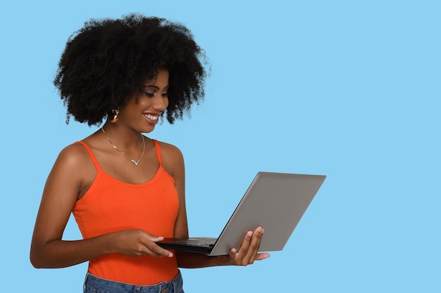 junge frau schaut auf den laptop-bildschirm des camputers und lächelt, schwarze frau auf blauem hintergrund