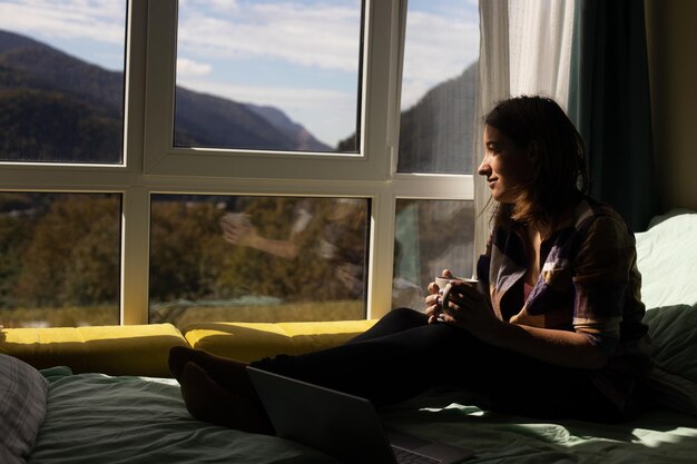 Foto junge frau schaut durch das fenster zu hause