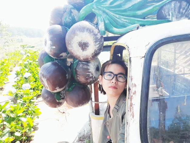 Foto junge frau schaut sich künstliche früchte an, während sie in einem pickup sitzt