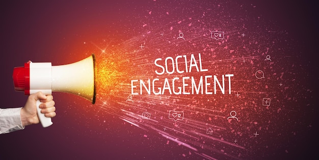 Junge Frau schreit auf Lautsprecher mit SOCIAL ENGAGEMENT Inschrift soziales Netzwerkkonzept.