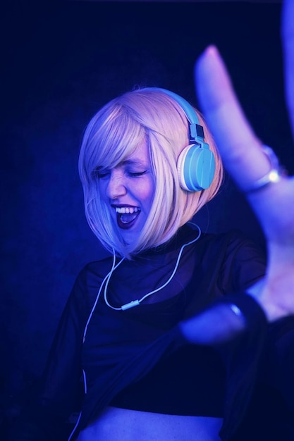 Junge Frau singt, während sie Musik vor schwarzem Hintergrund hört