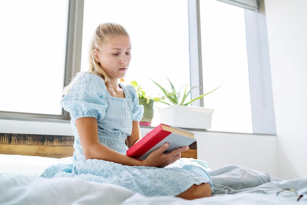 Junge Frau sitzt am Fenster und liest ein Buch