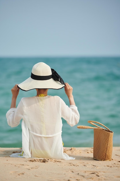 Junge Frau sitzt am Strand