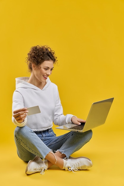 Junge Frau sitzt auf Beinen und hält Karte und Laptop