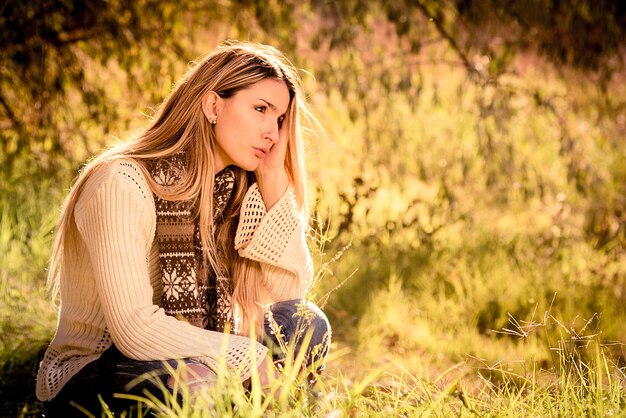 Foto junge frau sitzt auf dem feld