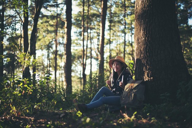 Foto junge frau sitzt auf einem baumstamm im wald