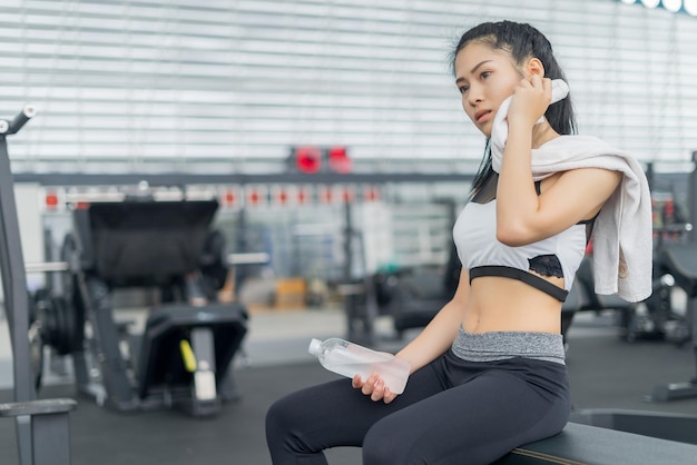 Junge Frau sitzt auf einer Bank im Fitnessstudio