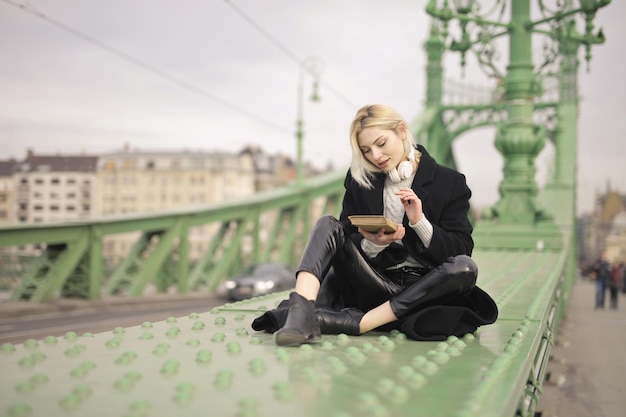 junge Frau sitzt auf einer Brücke in Budapest mit einem Buch in der Hand