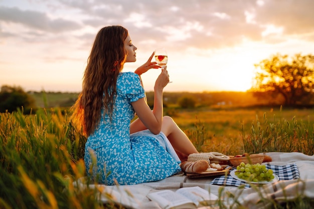 Junge Frau sitzt auf einer Platte mit einem Buch Sommerpicknick in der Natur Gesundes Essen