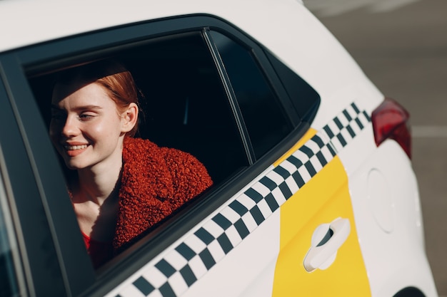 Junge Frau sitzt im Taxi auf dem Rücksitz.