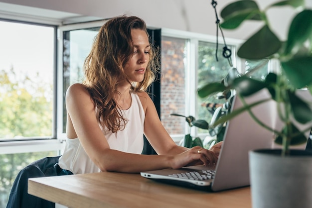 Junge Frau sitzt in der Küche und arbeitet am Laptop