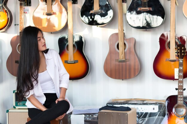 Foto junge frau sitzt in einem gitarrenladen