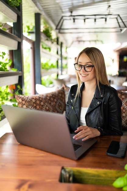 Junge Frau sitzt mit Laptop im Café