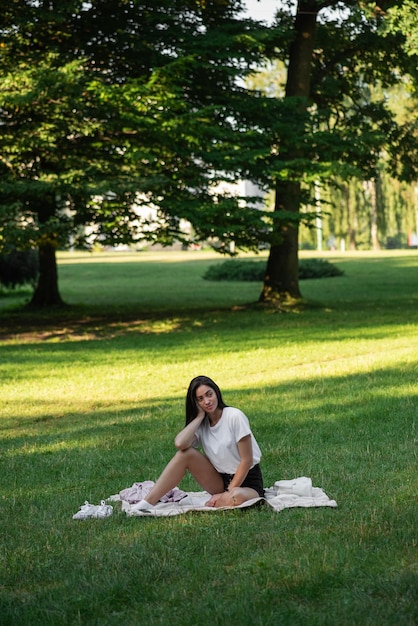 Junge Frau sitzt morgens auf einer Matte und meditiert im Park