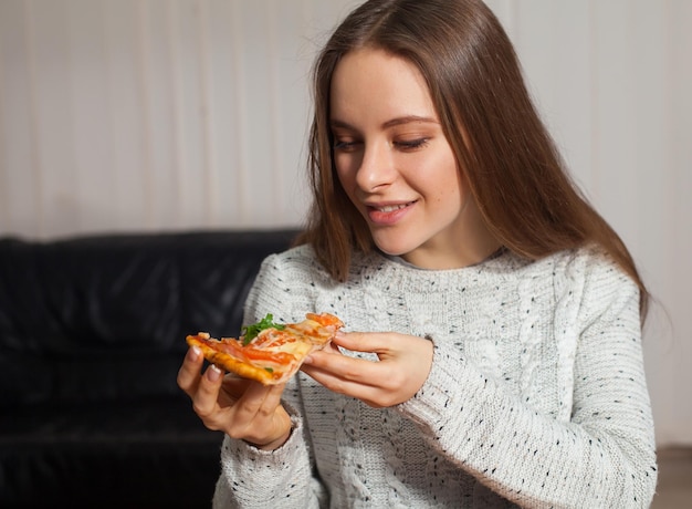 Junge Frau sitzt und geht Pizza essen