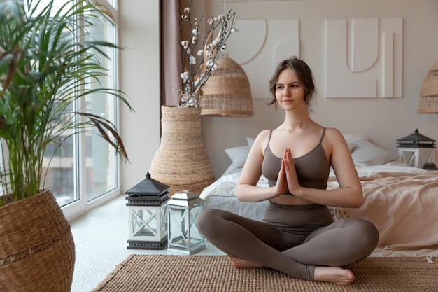 junge Frau sitzt zu Hause in der Yoga-Pose