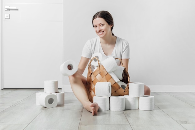 Junge Frau sitzt zu Hause neben einem Korb voller Toilettenpapier