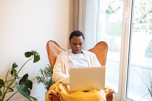 Junge Frau sitzt zu Hause und arbeitet von zu Hause aus mit Laptop Konzept Lifestyle-Telearbeit online