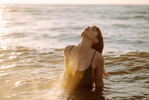 Junge Frau spaziert bei Sonnenuntergang am Meeresufer entlang. Natur-Relax-Lifestyle-Konzept